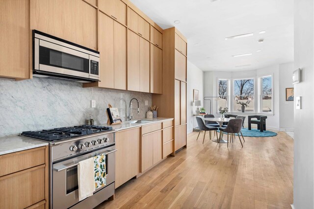 kitchen featuring appliances with stainless steel finishes, a sink, light brown cabinets, and light countertops