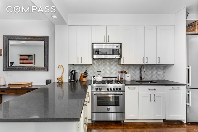 kitchen with a peninsula, white cabinetry, high end appliances, and a sink