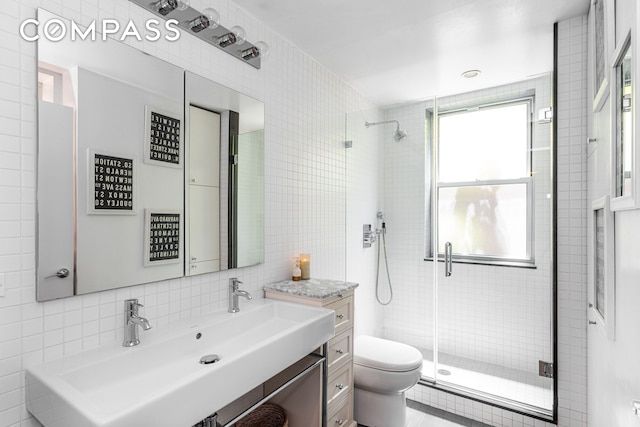 bathroom with a shower stall, decorative backsplash, a sink, toilet, and tile walls