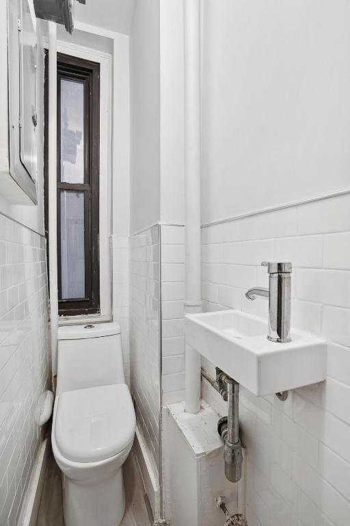 bathroom featuring tile walls, sink, and toilet