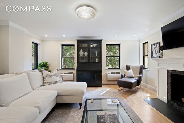 living room with a wall mounted air conditioner, crown molding, wood-type flooring, and a premium fireplace