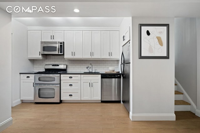 kitchen with sink, light hardwood / wood-style flooring, white cabinets, and appliances with stainless steel finishes