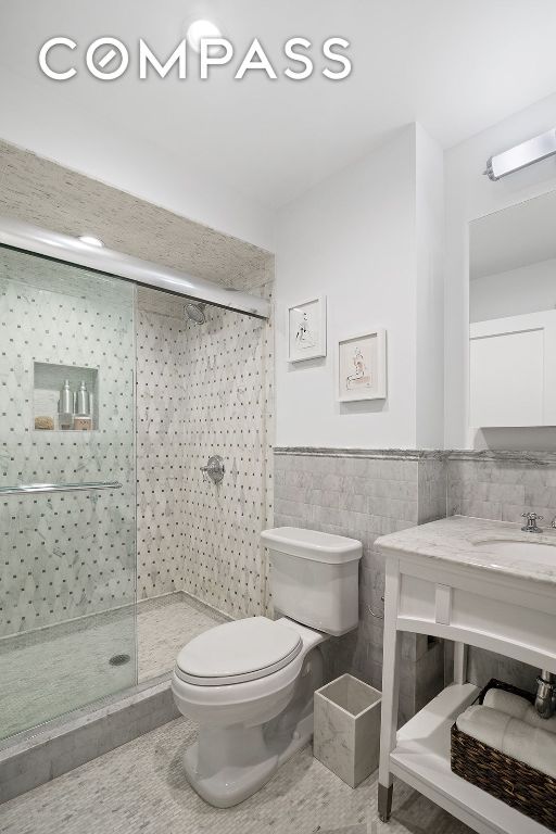 bathroom with tile walls, an enclosed shower, tile patterned floors, and toilet