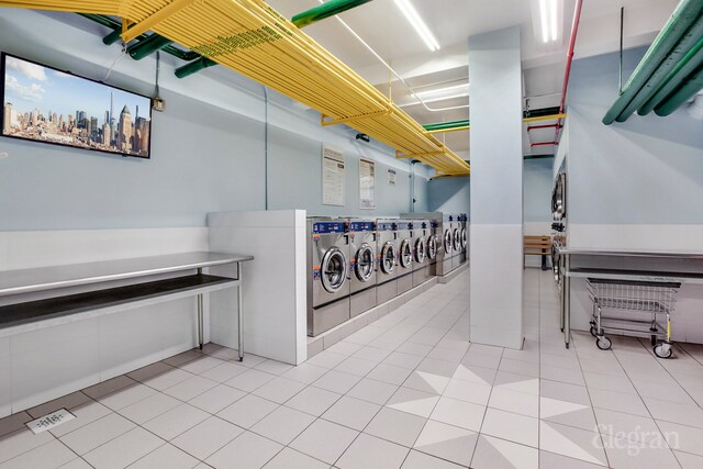 community laundry room featuring washer and clothes dryer, light tile patterned flooring, and a city view