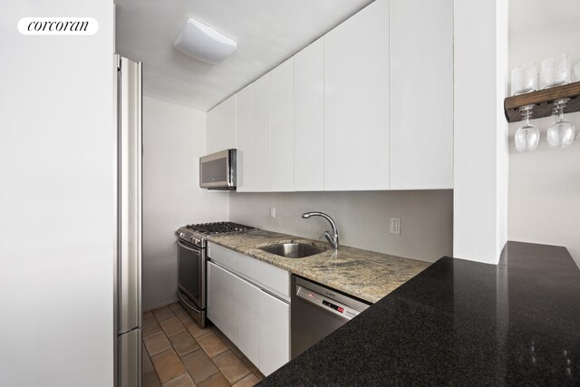 32 Gramercy Park S Unit 7F, New York City, NY 10003 - kitchen with stainless steel appliances, a sink, white cabinetry, dark stone counters, and modern cabinets