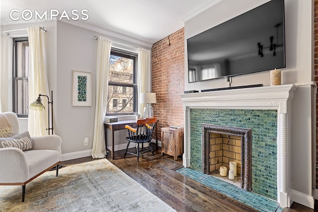 sitting room with baseboards, crown molding, a tiled fireplace, and wood finished floors