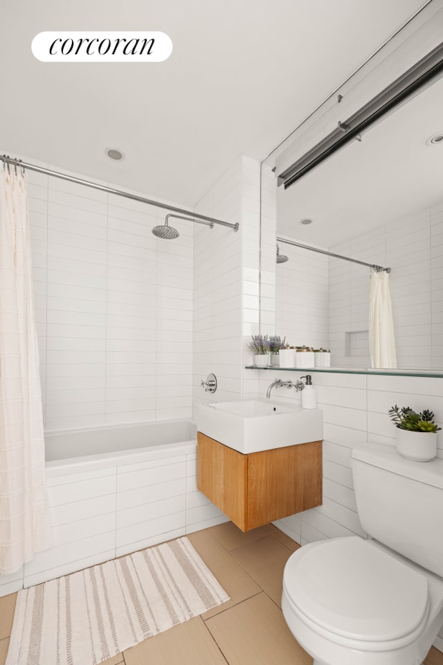 bathroom featuring tiled shower / bath, tile walls, toilet, vanity, and tile patterned flooring