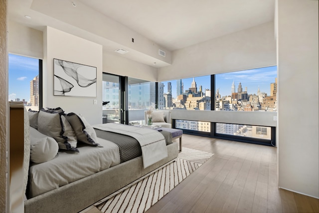 bedroom with a view of city, visible vents, and hardwood / wood-style floors