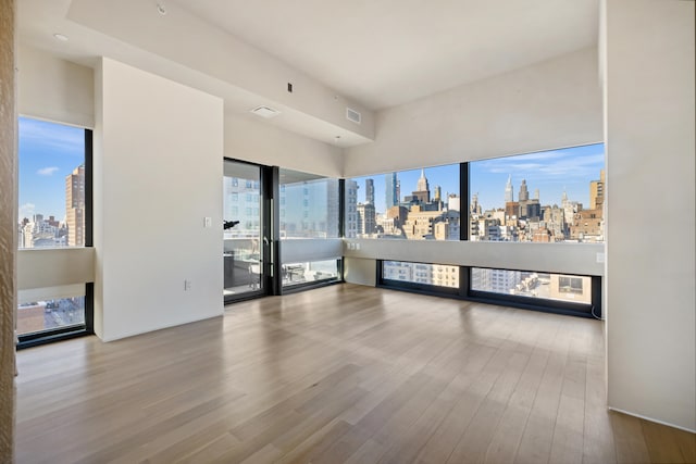 spare room featuring wood finished floors, visible vents, and a city view