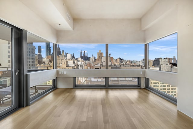 empty room with a view of city, visible vents, and wood finished floors