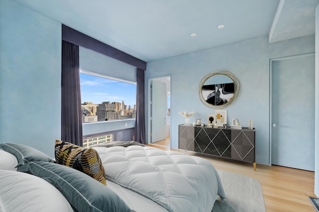 bedroom with a view of city and wood finished floors