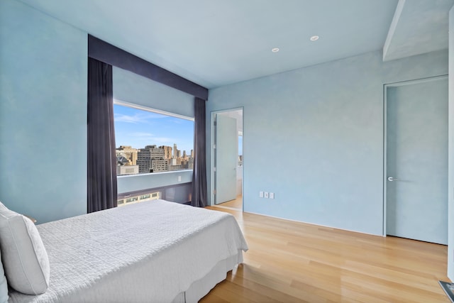 bedroom featuring wood finished floors and a city view