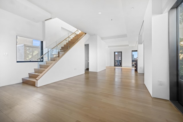 unfurnished living room featuring stairs and wood finished floors