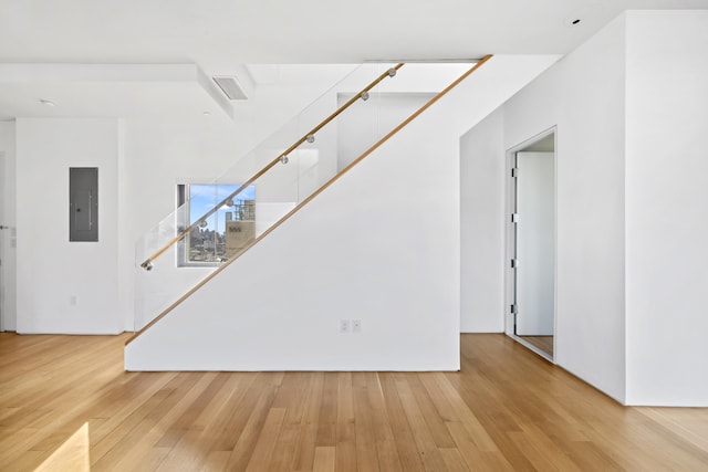 unfurnished living room featuring stairs, hardwood / wood-style flooring, and electric panel