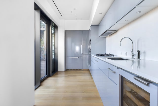 kitchen featuring wine cooler, light countertops, a sink, and modern cabinets