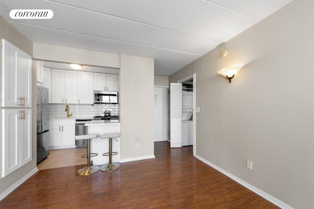 kitchen with appliances with stainless steel finishes, dark hardwood / wood-style floors, a breakfast bar area, and white cabinets