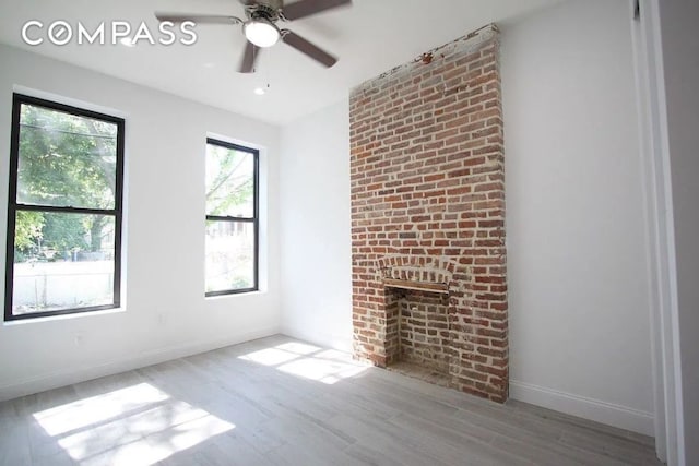 unfurnished living room featuring ceiling fan, a fireplace, and light hardwood / wood-style floors