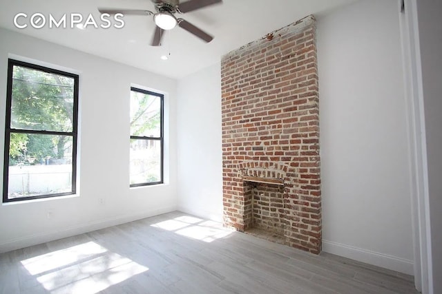 unfurnished living room with a fireplace, baseboards, ceiling fan, and wood finished floors