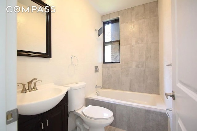 full bathroom with vanity, toilet, tiled shower / bath combo, and tile walls