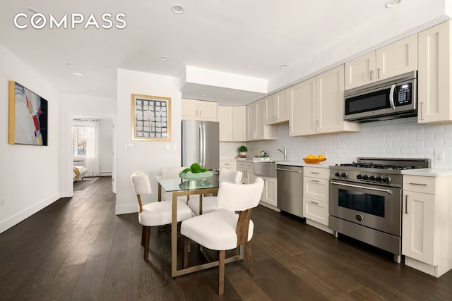 kitchen with decorative backsplash, appliances with stainless steel finishes, light countertops, and dark wood-style flooring