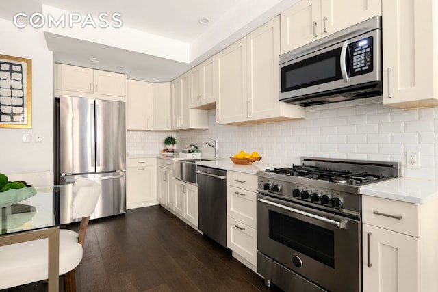 kitchen with tasteful backsplash, stainless steel appliances, light countertops, and dark wood-type flooring