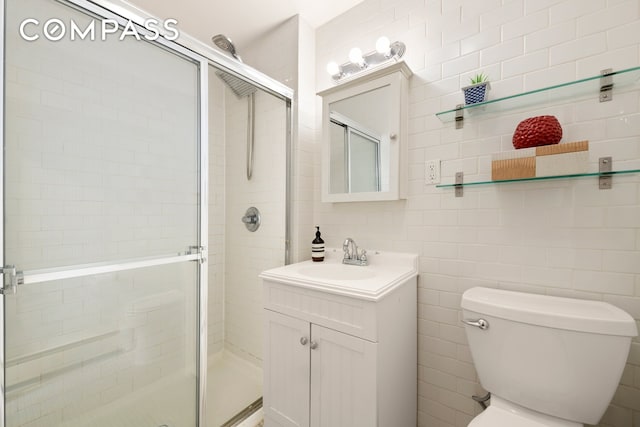 full bath with vanity, a shower stall, toilet, and tile walls