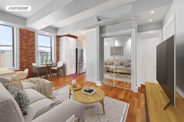 living room featuring brick wall and light wood-type flooring