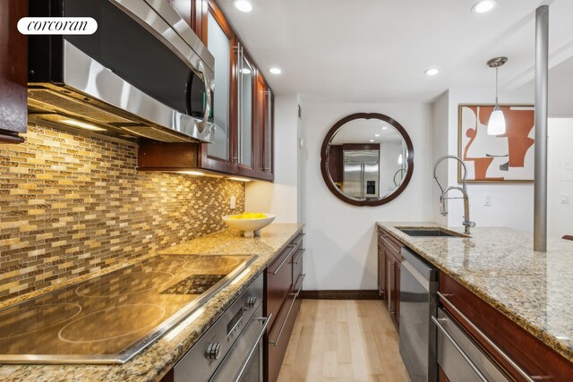 laundry room with cabinets, stacked washing maching and dryer, sink, and light hardwood / wood-style flooring