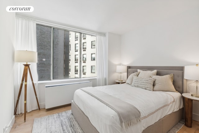 bedroom with visible vents, radiator, and wood finished floors