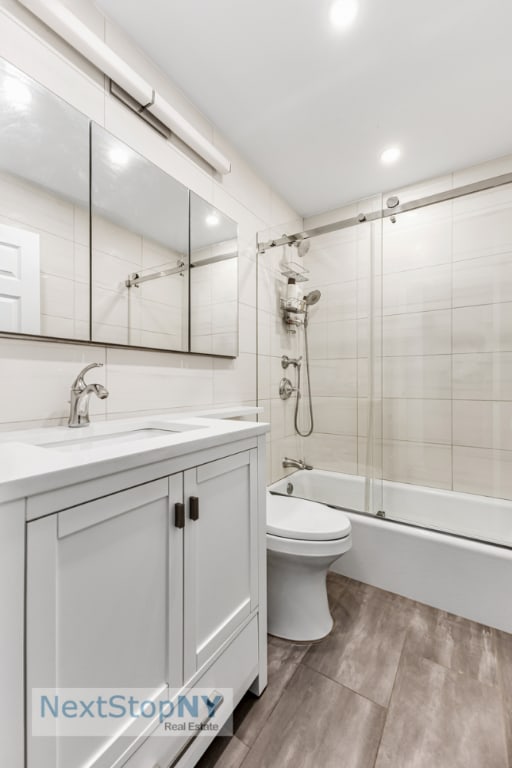 full bathroom featuring vanity, hardwood / wood-style flooring, toilet, and combined bath / shower with glass door