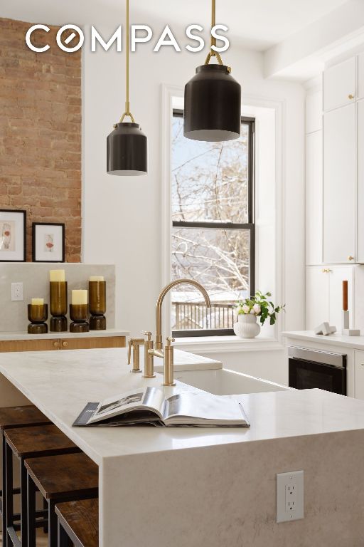 kitchen featuring a breakfast bar, a wealth of natural light, white cabinets, and decorative light fixtures