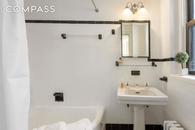 bathroom featuring radiator heating unit, tile walls, and a tub to relax in