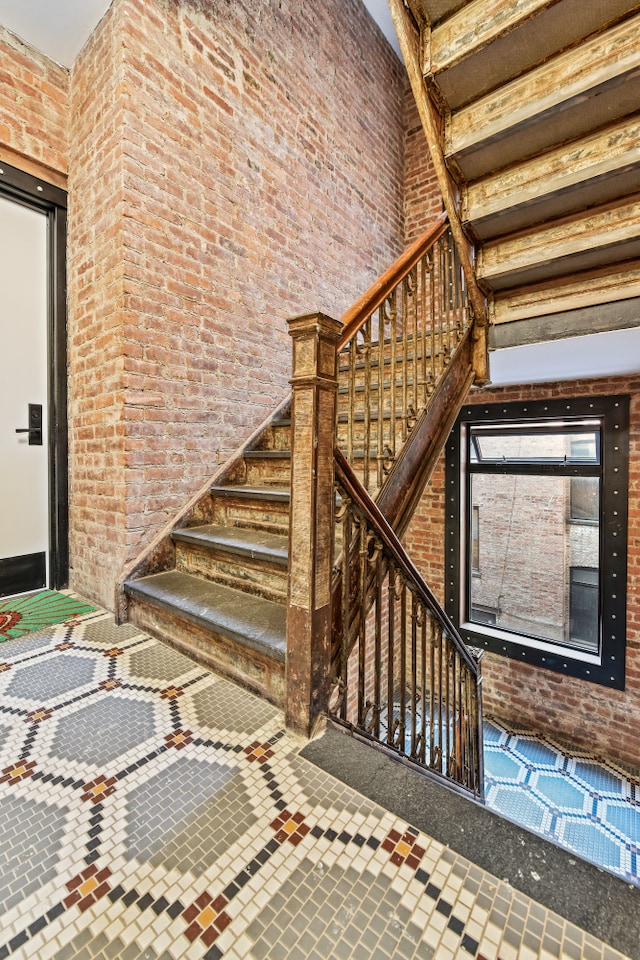 stairs featuring brick wall and a high ceiling