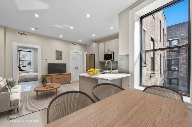 interior space with stainless steel appliances, light countertops, open floor plan, white cabinetry, and a peninsula