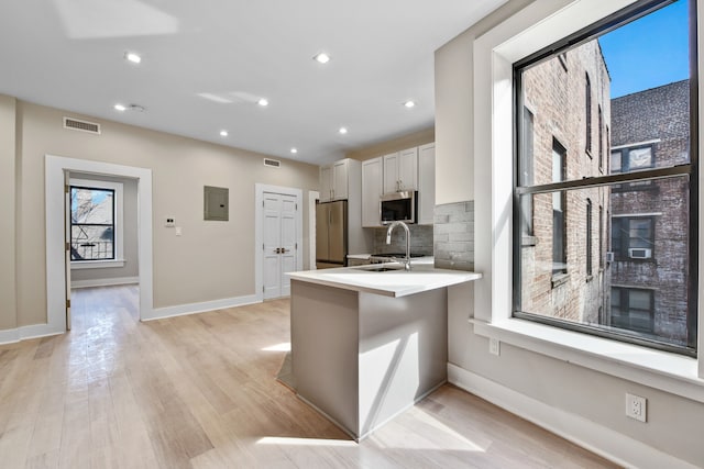 kitchen with a peninsula, a breakfast bar, white cabinetry, light countertops, and appliances with stainless steel finishes