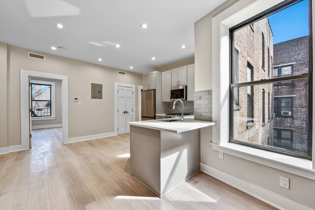 kitchen with visible vents, a sink, backsplash, appliances with stainless steel finishes, and a peninsula