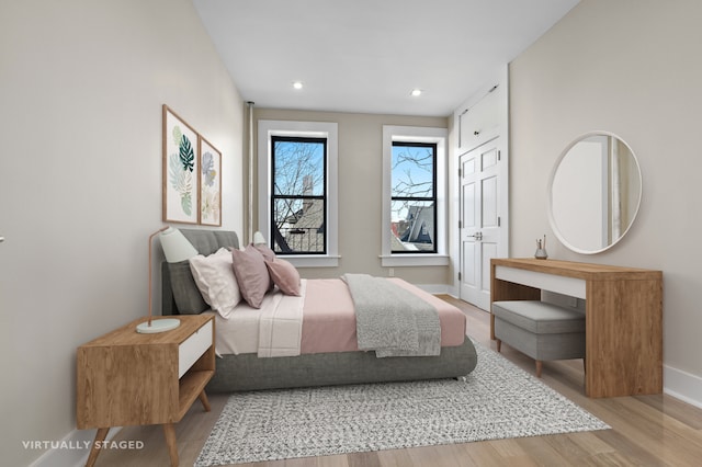 bedroom featuring baseboards, wood finished floors, and recessed lighting