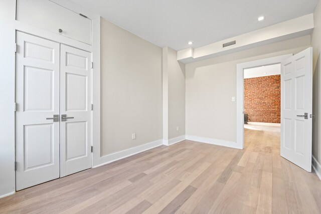 unfurnished bedroom featuring visible vents, recessed lighting, brick wall, light wood finished floors, and baseboards