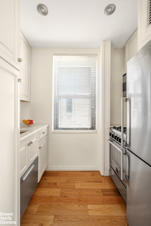 kitchen featuring stainless steel appliances, white cabinetry, and light hardwood / wood-style flooring