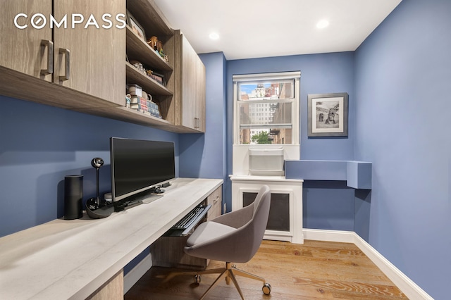 office featuring light wood finished floors, baseboards, built in desk, and recessed lighting