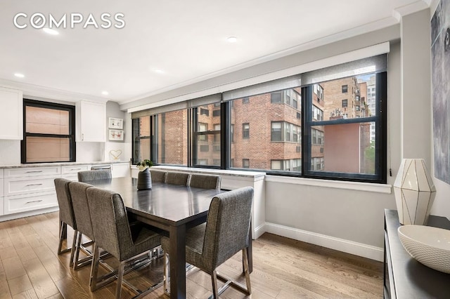 dining room featuring crown molding, light wood-type flooring, and a wealth of natural light