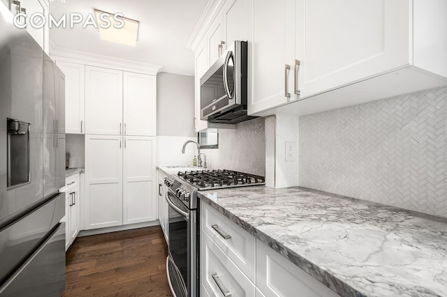 kitchen featuring light stone counters, stainless steel appliances, decorative backsplash, dark wood-type flooring, and white cabinets