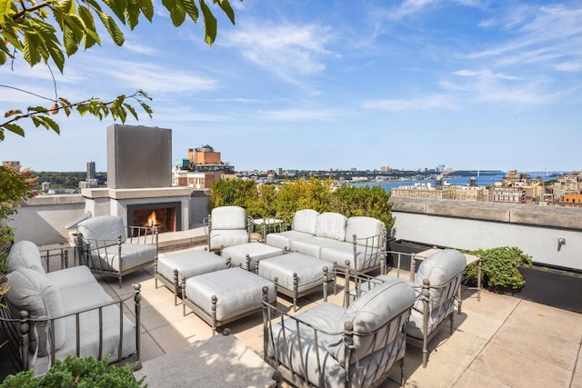 view of patio featuring an outdoor living space with a fireplace and a water view