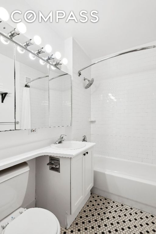 full bathroom with tiled shower / bath combo, vanity, and toilet