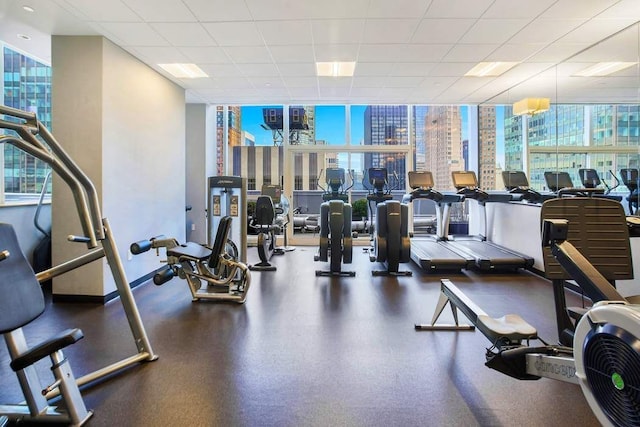 exercise room with floor to ceiling windows and baseboards