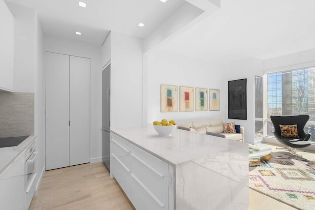 kitchen featuring white oven, light wood-style floors, and modern cabinets