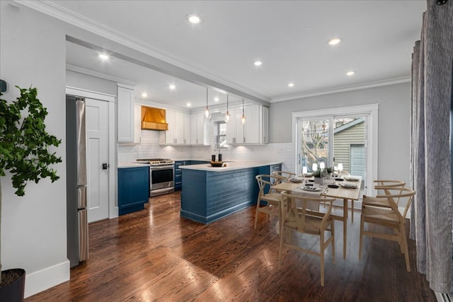 kitchen featuring pendant lighting, white cabinetry, stainless steel appliances, blue cabinetry, and custom range hood