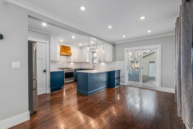 kitchen featuring blue cabinetry, premium range hood, white cabinetry, hanging light fixtures, and stainless steel appliances