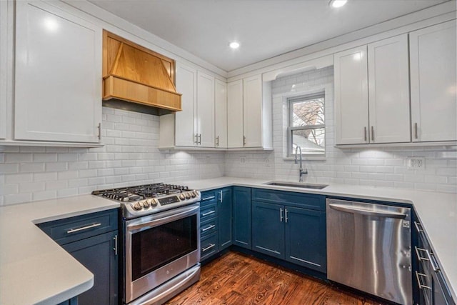 kitchen featuring premium range hood, blue cabinetry, sink, white cabinetry, and appliances with stainless steel finishes