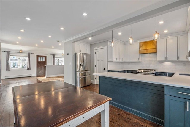 kitchen with appliances with stainless steel finishes, white cabinetry, a baseboard radiator, hanging light fixtures, and custom exhaust hood